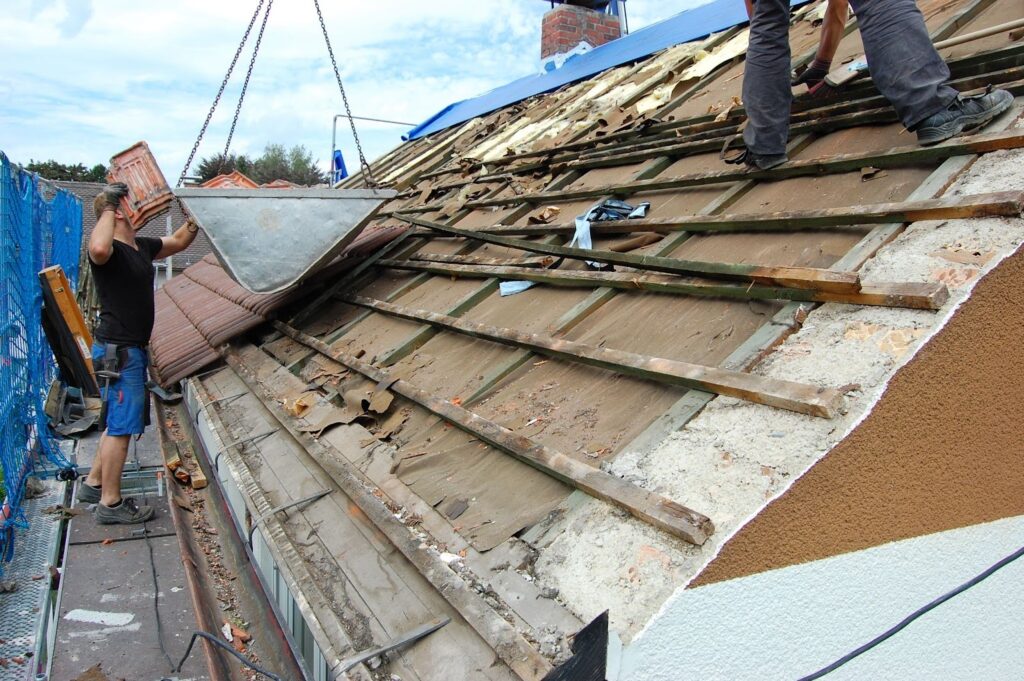 A roofer removes the old roof tiles to prepare for a new installation.